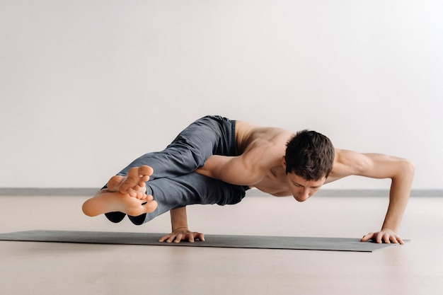 A man with a bony torso trains lying down, doing a handstand in the gym