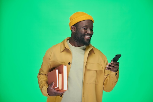 Man with books reading message on the phone