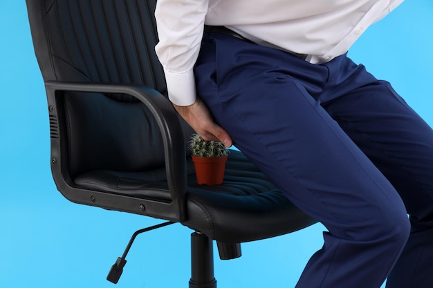 Man with bottom pain on blue background. Hemorrhoids concept