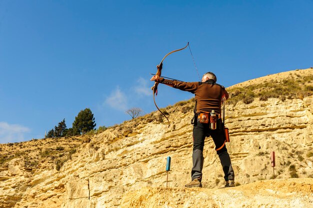 Man with bow and arrow practicing archery in park