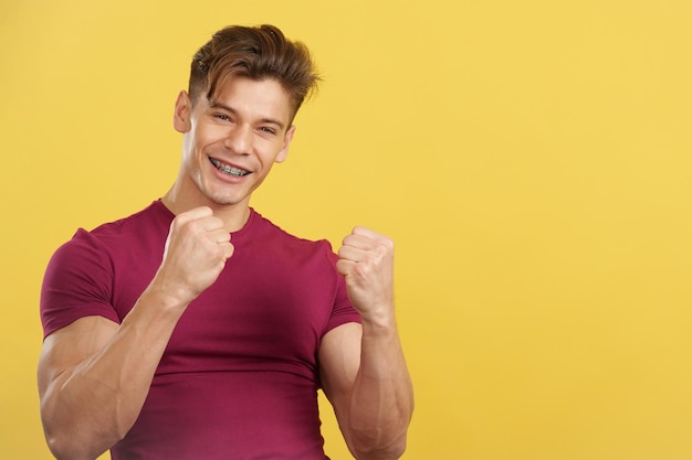 Man with brackets celebrating with fists raised