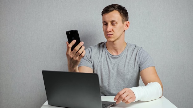 Man with broken arm works talking through video call