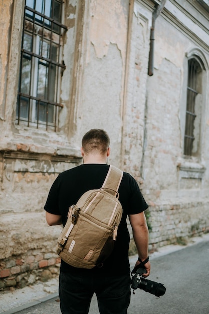 Foto un uomo con una borsa da fotocamera marrone e una fotocamera in mano che cammina in una vecchia città