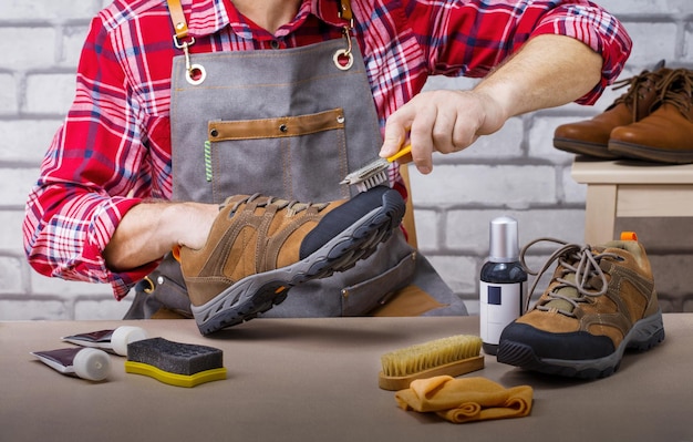 Man with brush cleans suede shoes. Shoe care and shine concept.