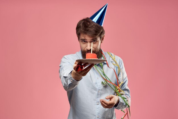 Man with cake in a plate and in a blue shirt on a pink background birthday holidays cropped view person