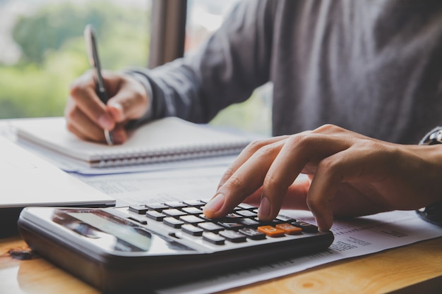 Man with calculator counting making notes at office hand is writes in a notebook