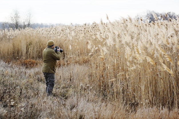 A man with a camera on a background of yellow high grass. Photographer landscape