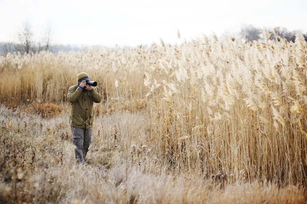 A man with a camera on a background of yellow high grass. Photographer landscape