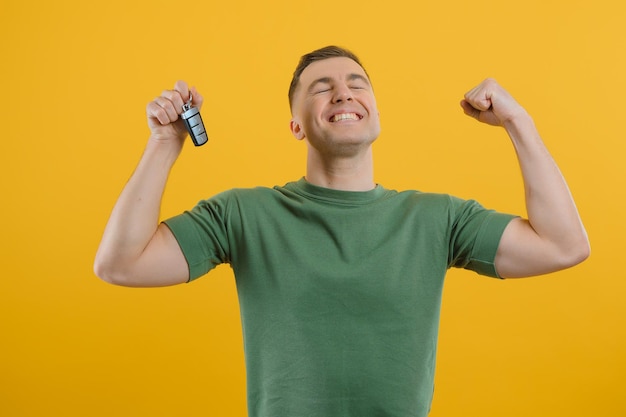 Man with car keys on a yellow background, buying a new car