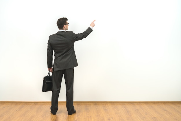The man with a case gesturing on the white wall background
