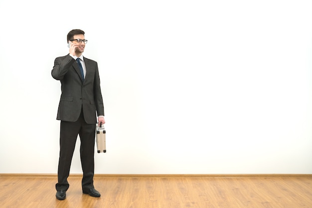 The man with a case phones on the white wall background