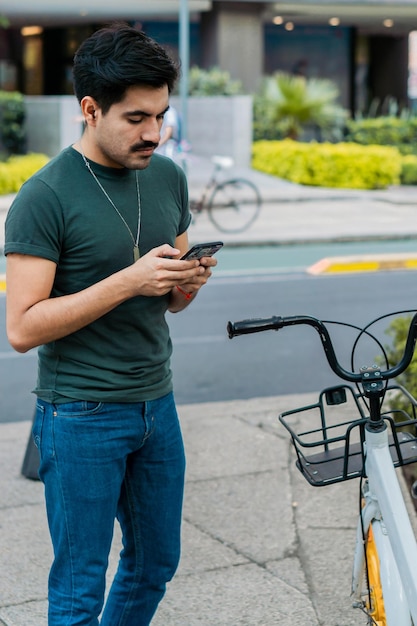 Man with cell phone to unlock bicycle for transportation to work.