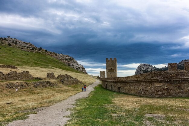 A man with a child against the background of an ancient Genoese fortress with a stormy sky Sudak