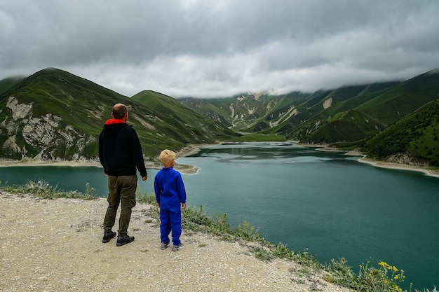 A man with a child on the background of Lake Kezenoyam in the Caucasus mountains in Chechnya Russia June 2021