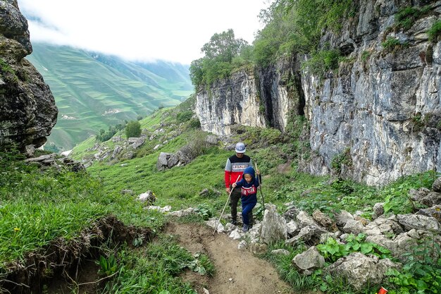 雲の中の山の風景を背景に子供を持つ男ダゲスタンロシアの石のボウル