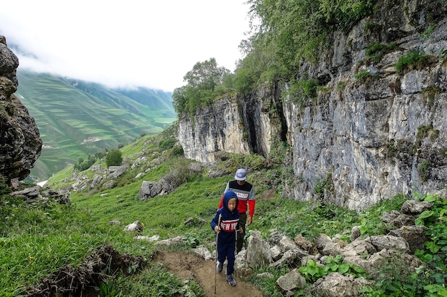 雲の中の山の風景を背景に子供を持つ男ダゲスタンロシアの石のボウル