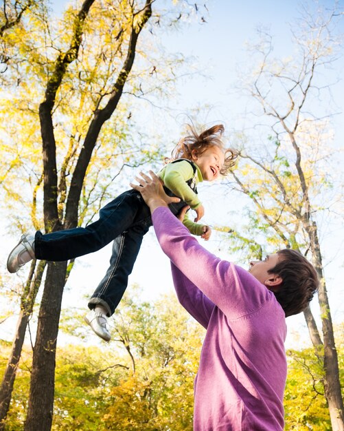 Man with child having fun in autumn park. Focus on man