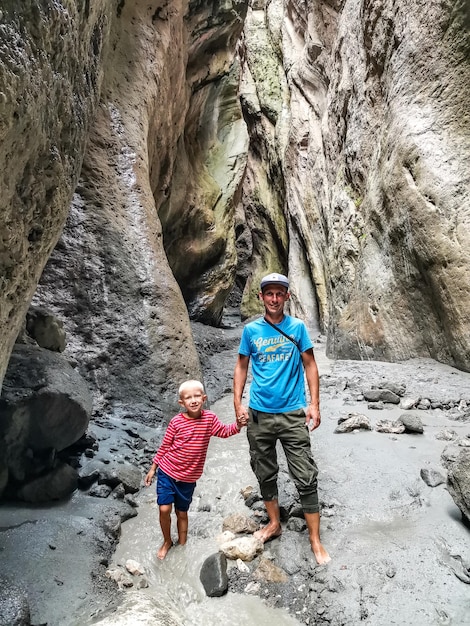 A man with a child in a narrow mountain gorge Karadakh in the sunlight in Dagestan Russia June 2021