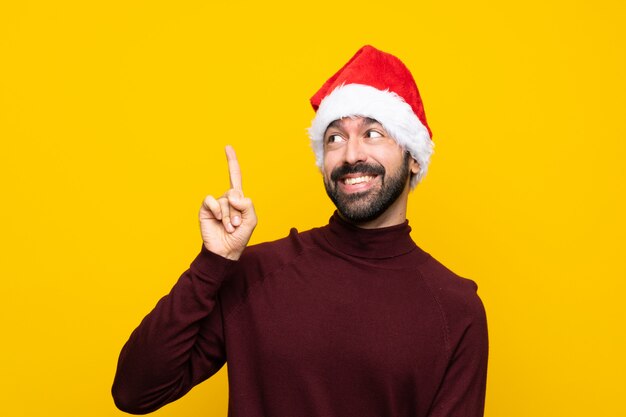 Uomo con cappello di natale su sfondo giallo isolato che intende realizzare la soluzione mentre si solleva un dito