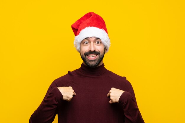 Man with christmas hat over isolated yellow background with surprise facial expression