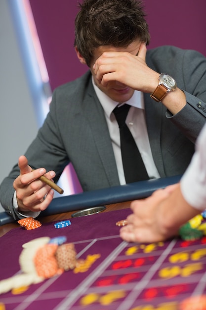 Foto uomo con sigaro pensando al tavolo della roulette