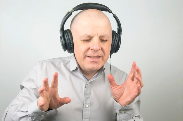 Man with closed eyes listens to music with headphones on a light background
