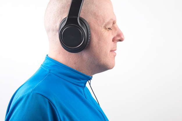 Man with closed eyes listens to music with headphones on a light background