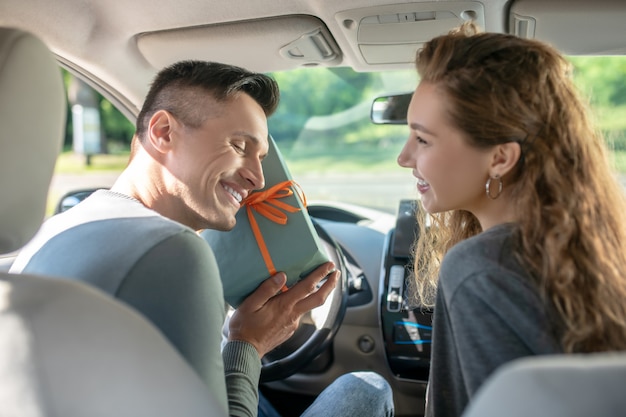 Man with closed eyes with box near woman in car