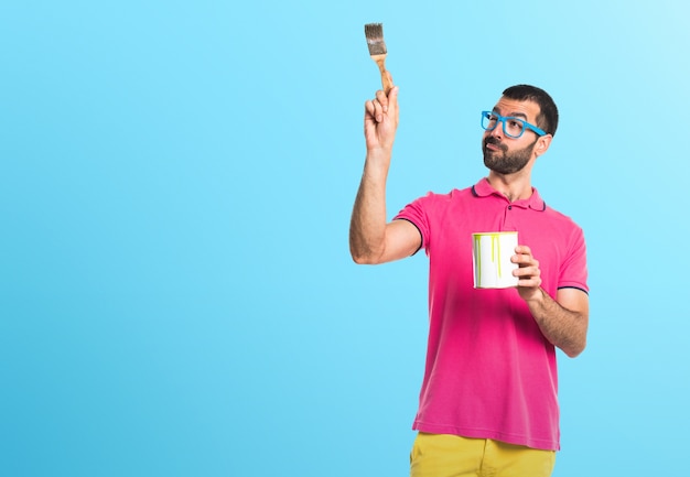 Man with colorful clothes holding a paint pot on colorful background