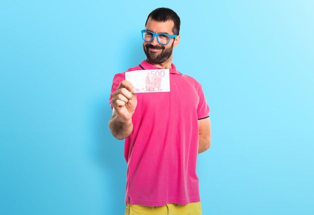 Man with colorful clothes taking a lot of money on colorful background