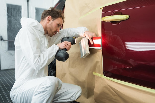 Man with a colorists lamp in a vehicle painting booth