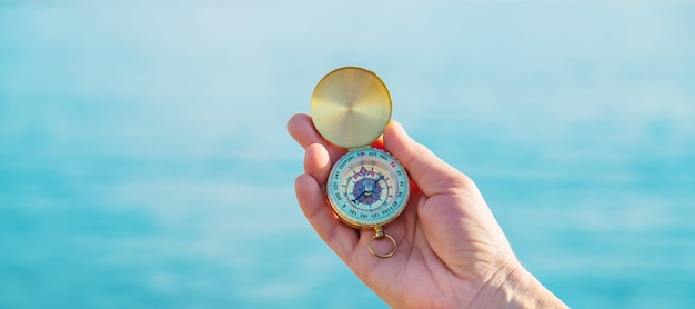 A man with a compass in his hands near the sea. Selective focus.