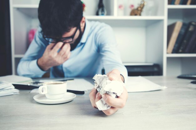 Photo man with crumpled paper on table