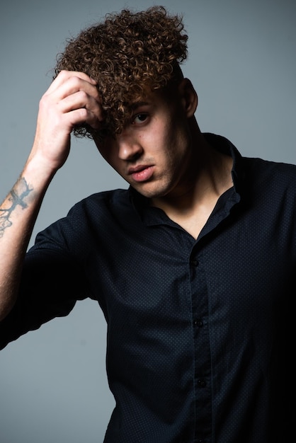 A man with curly hair wears a black shirt with the word " love " on it.