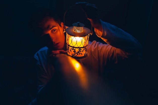 Photo man with decorative yellow lamp in dark. soft focus