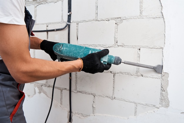 Man with demolition hammer removing stucco from wall