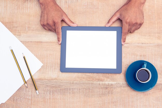 Man with digital tablet over table by coffee and papers