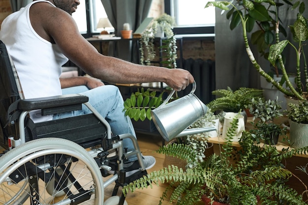 Мужчина с инвалидностью ухаживает дома за цветами