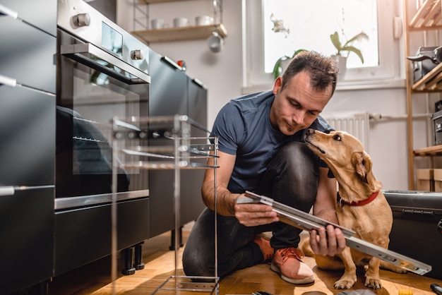 Man with dog building kitchen cabinets