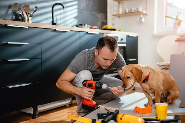 Man with dog building kitchen cabinets