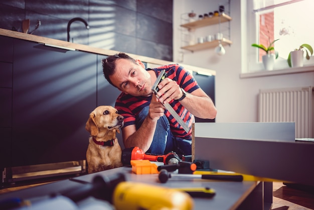 Man with dog building kitchen cabinets