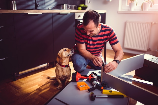 Man with dog building kitchen cabinets