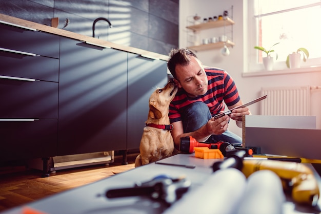 Man with dog building kitchen cabinets