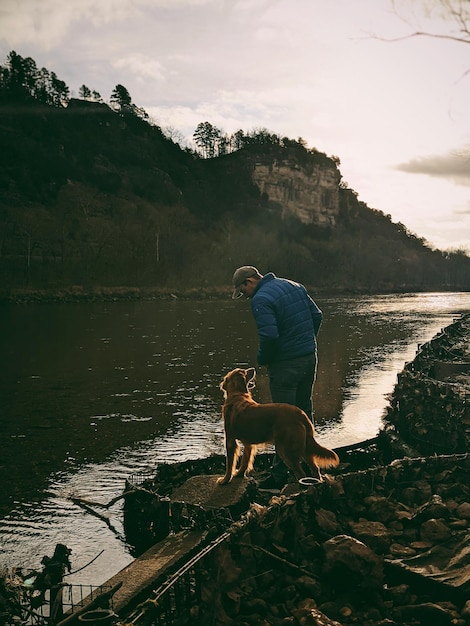 man with dog on lake against sky
