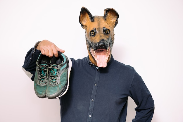 Man with dog mask holding a pair of running shoes