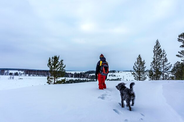 Man with dog on snow against sky