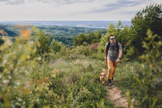 ハイキングトレイルを歩いている犬を持つ男