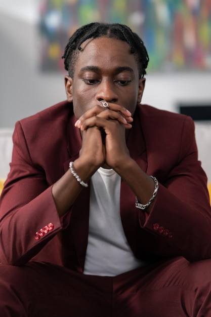Man with dreadlocked wearing smart suit sitting in office hands resting on knees