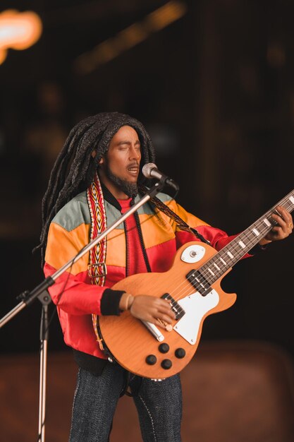 Photo a man with dreadlocks is playing a guitar