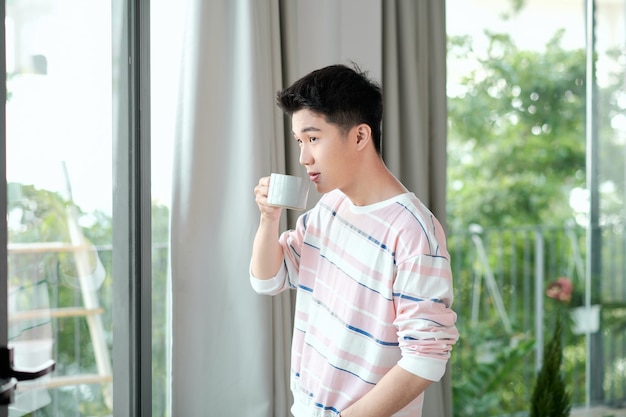 Man with drink near window indoors. Lazy morning